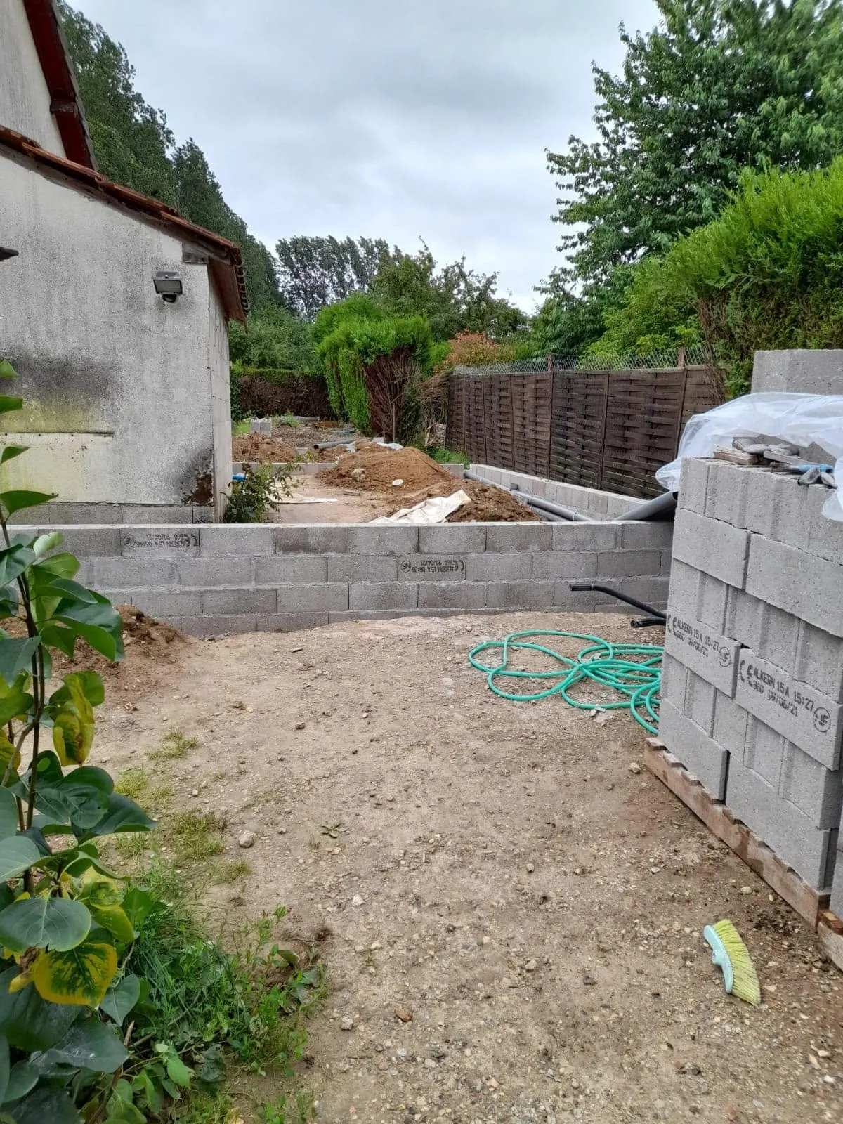 Terrain dégagé et premiers rangs de parpaings à côté de la maison