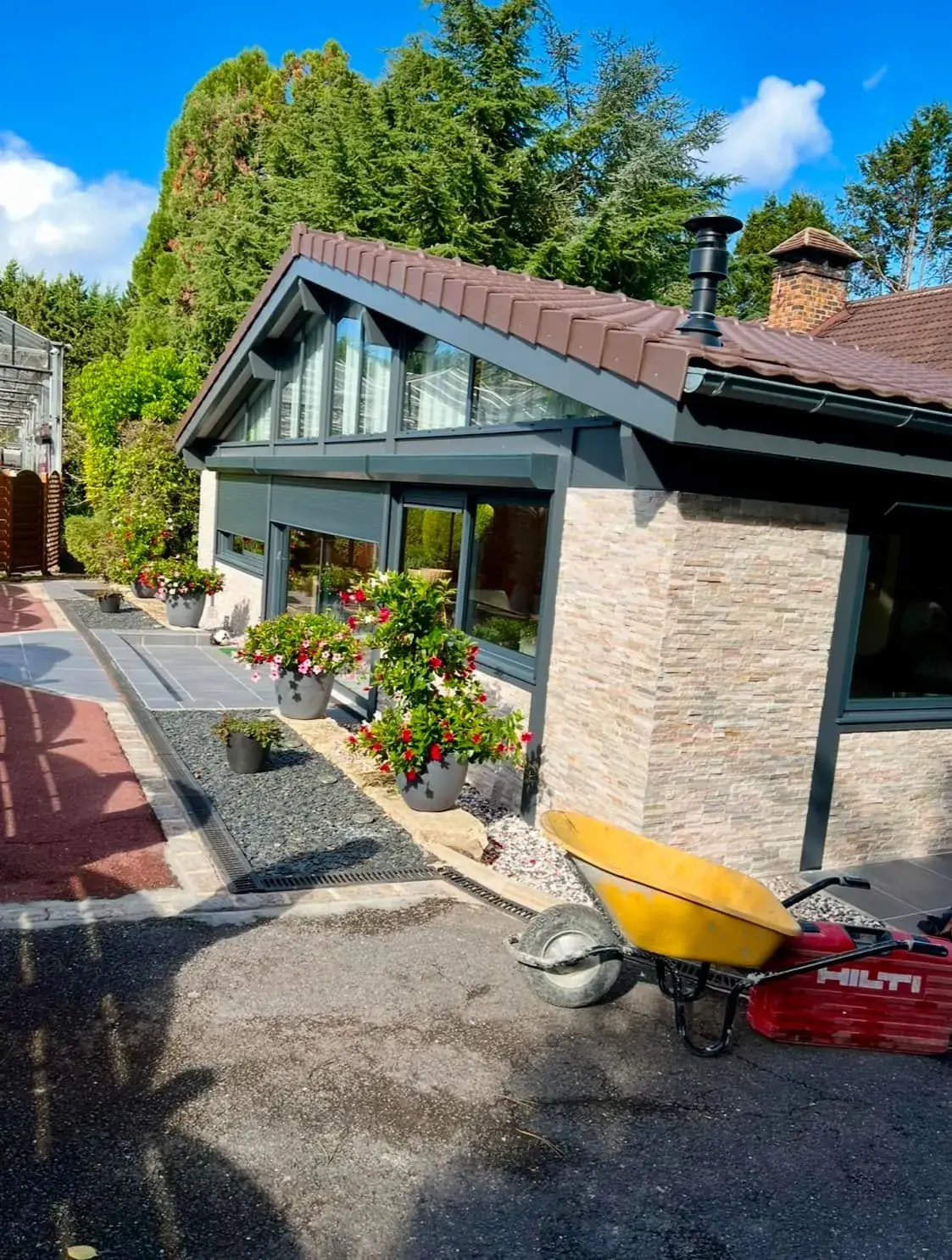 Extension finie, toiture neuve et parement en pierre, ouverte sur le jardin