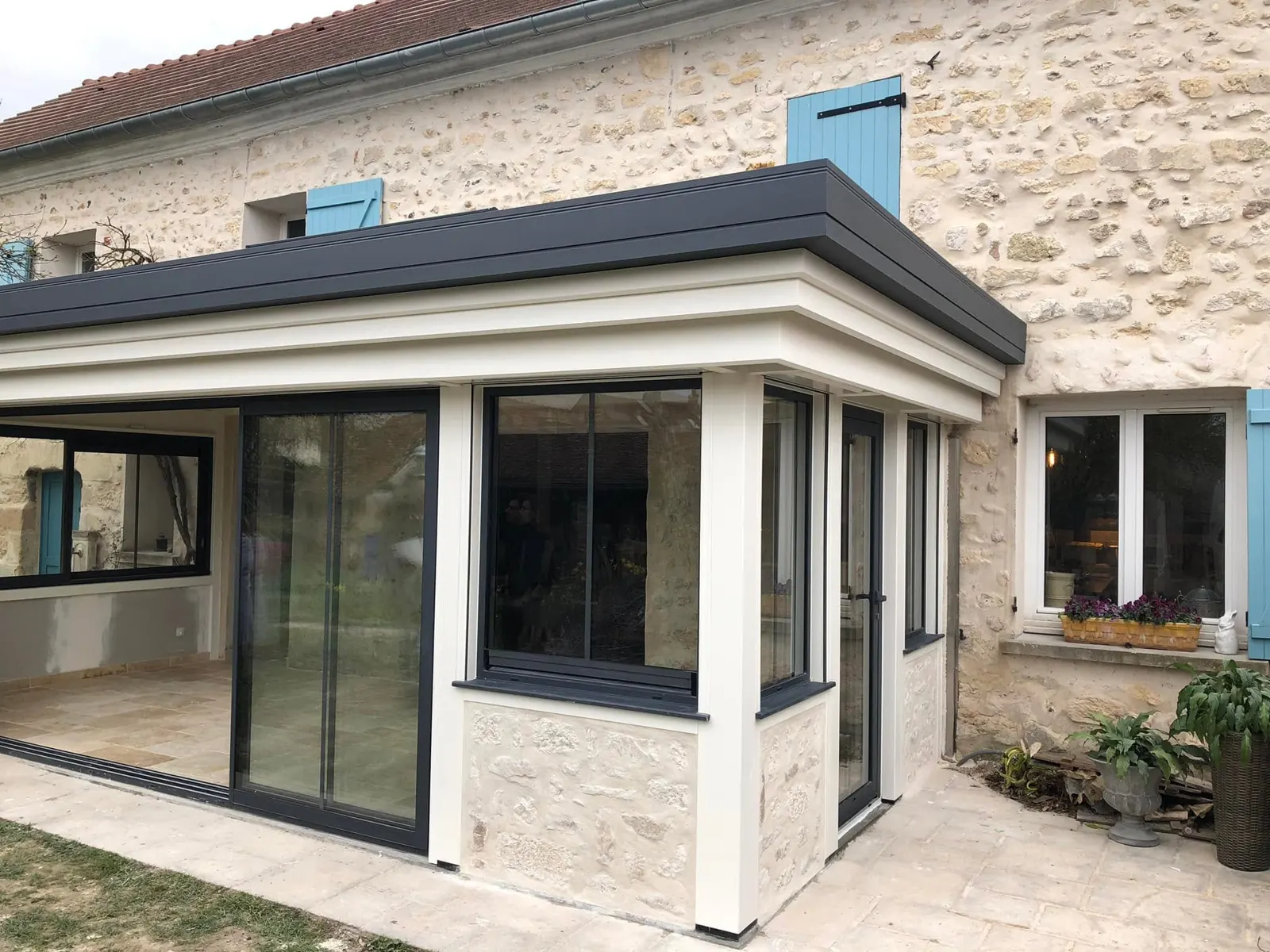 Véranda neuve accolée à une maison en pierre